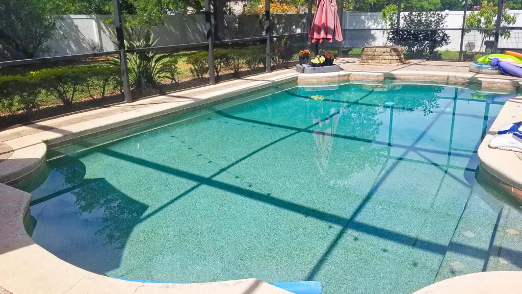 The same screened pool restored to clear blue water after the clean-up