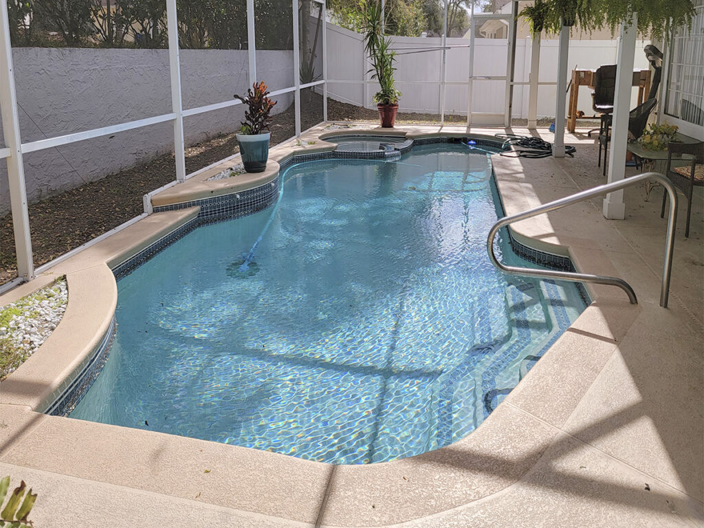 Freshly cleaned screened pool with tiled waterline and stainless handrail
