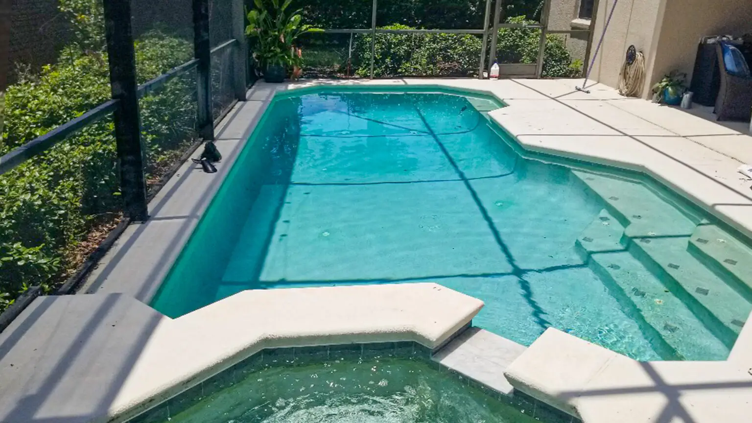 Clear blue screened pool with attached spa after weekly service